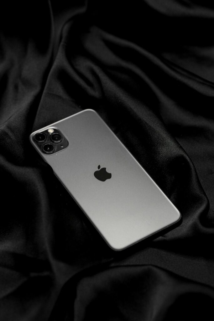 Elegant smartphone placed on smooth black satin fabric, showcasing modern technology and design.